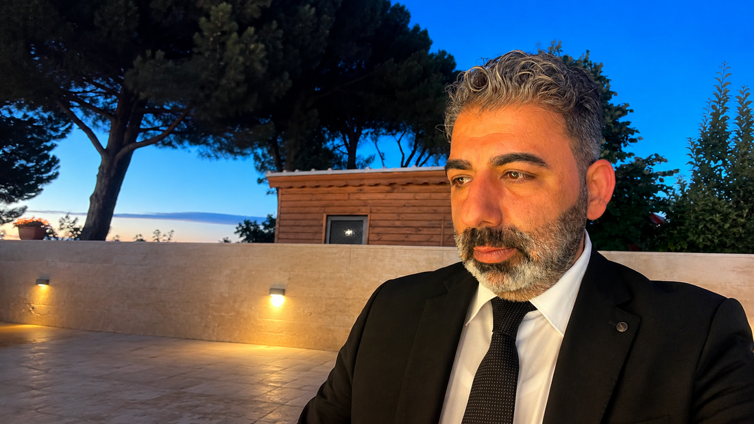 Ayhan Çabuk von Green Agora im Anzug vor mediterraner Abendkulisse | persönliche Geschichte hinter Green Agora